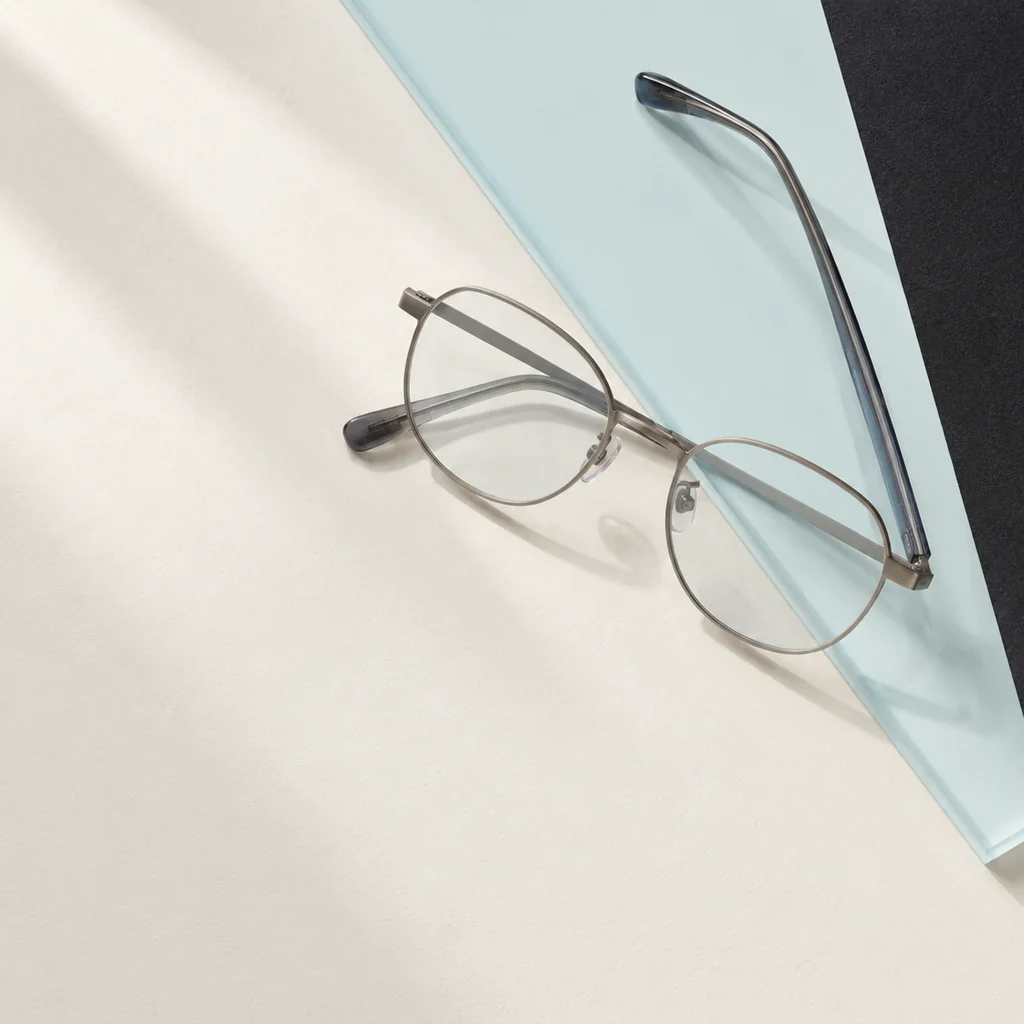 Round spectacles placed across pale-blue acetate and cream paper
